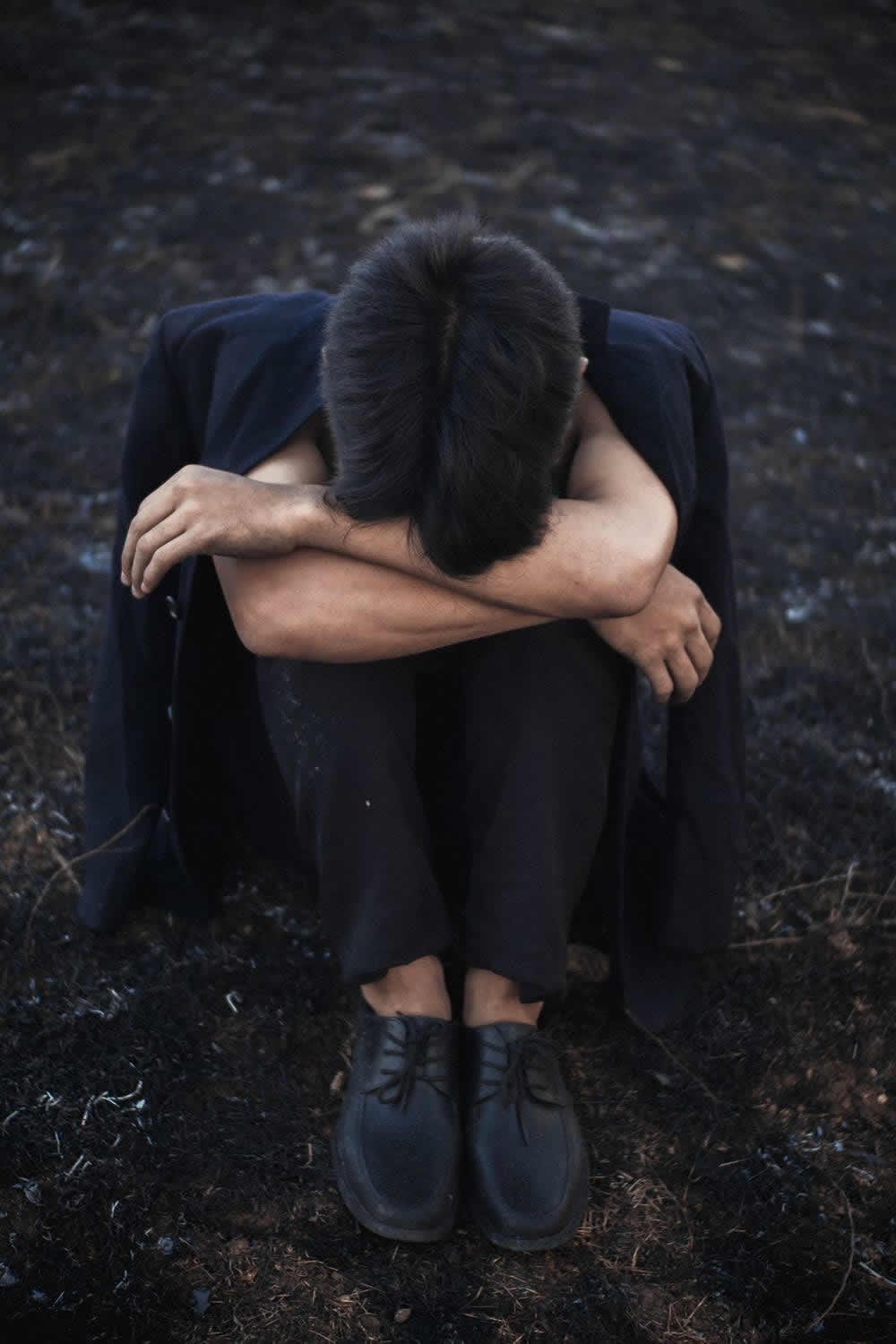 person sitting with head laying in knees